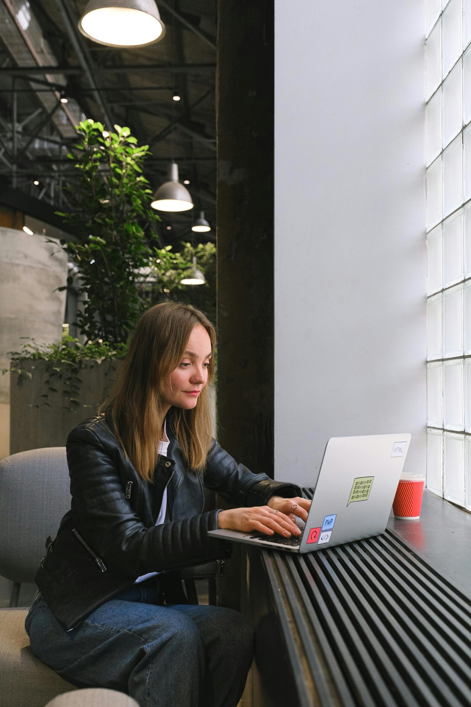 Woman freelancer using laptop indoors in a stylish office setting with natural light.